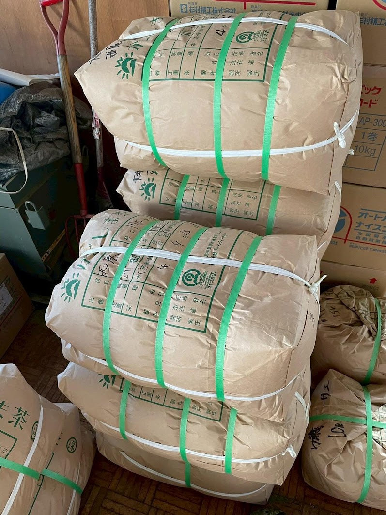 Bags of harvested tencha leaf stacked at a Japanese tea farm before stone milling into matcha powder